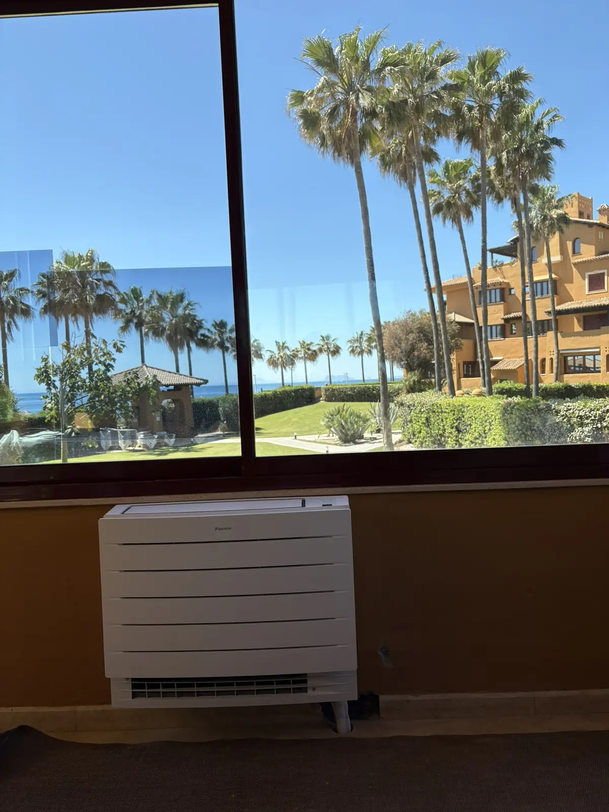Consola de climatización Daikin instalada bajo un ventanal con vistas al mar en Estepona